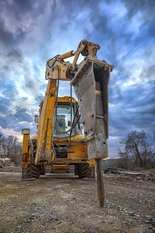 Excavator with hydraulic breaker hammer for the destruction of concrete and hard rock at the construction site or quarry.