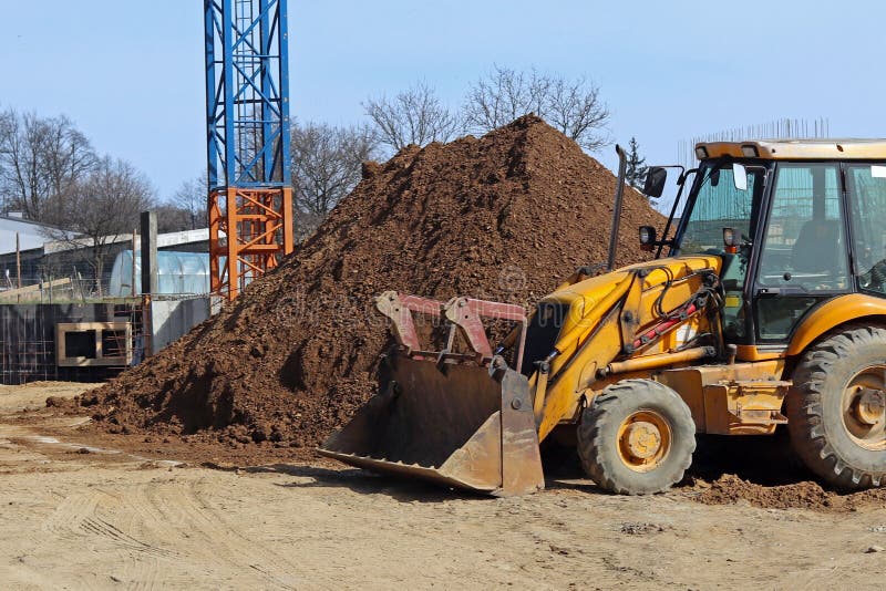 The excavator loads the load on the car. Construction works. Technology of urbanization. Heavy industrial machines. Building of th stock image The excavator loads the load on the car. Construction works. Technology of urbanization. Heavy industrial machines. Building of th stock image