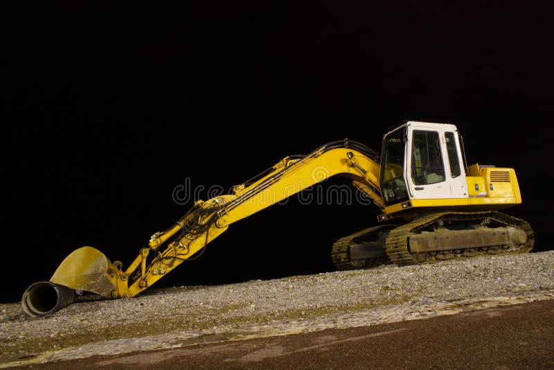 Excavator on night pebble beach