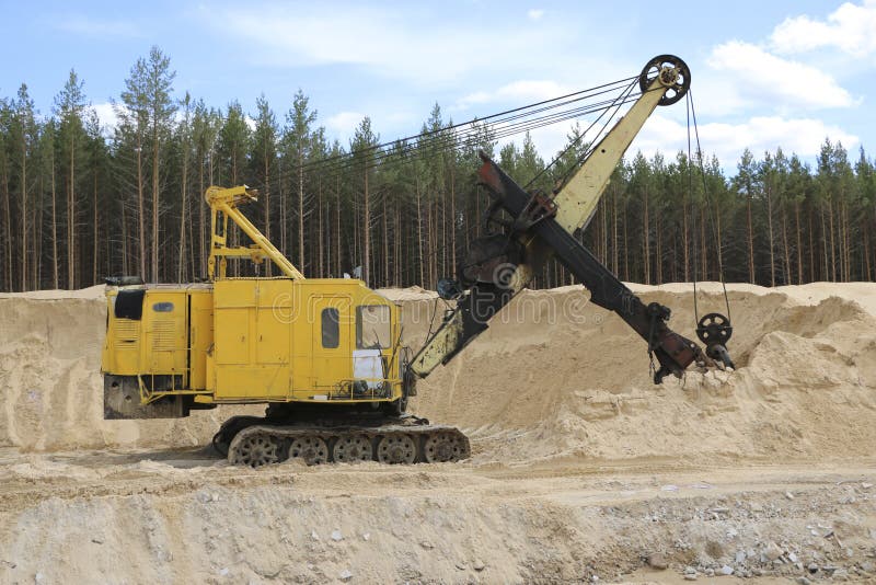 Excavators at a Sand Quarry. Big orange digger in open sand mine is waiting for new shift.