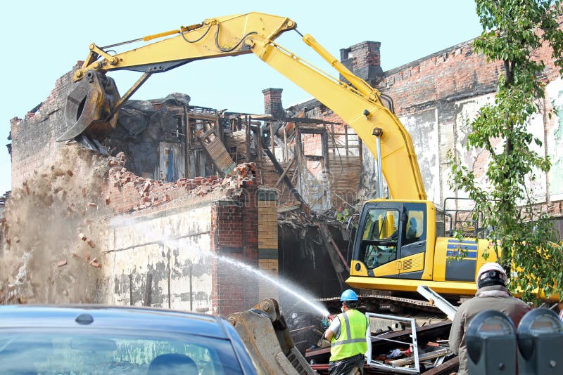 An excavator demolishing a damaged building. An excavator demolishing a damaged building