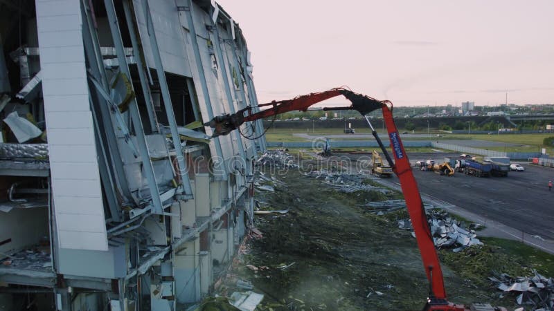 Excavatrice avec longues la patinoire de hockey abandonnée de bras par ruines banque de vidéos