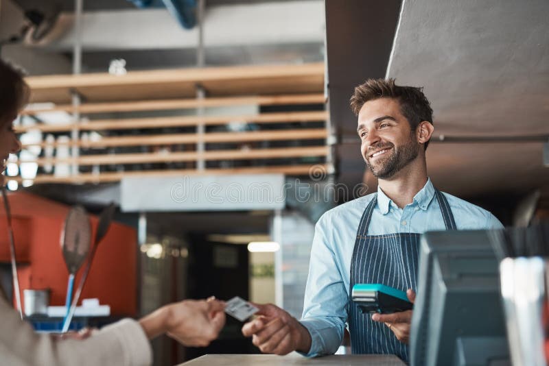 Excellent service is simply a part of the job. a waiter processing a credit card payment from a customer in a cafe.