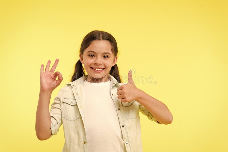 Excellente qualit? La fille d'enfant montre le pouce et le fond correct de jaune de geste L'enfant recommandent fortement l'excel photo libre de droits Excellente qualit? La fille d'enfant montre le pouce et le fond correct de jaune de geste L'enfant recommandent fortement l'excel photo libre de droits