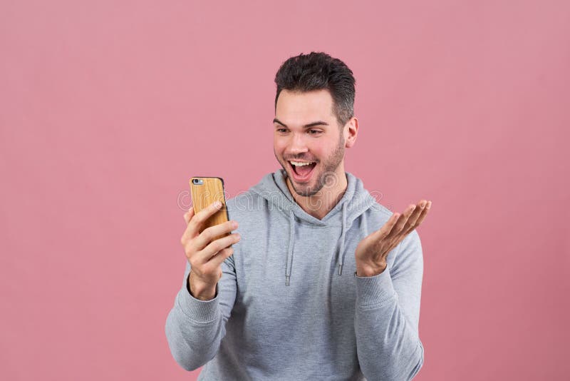 Excitan al individuo joven deportivo sobre el nuevo móvil app y entusiasta sonrisa y agitar sus manos que miran el teléfono fotos de archivo libres de regalías Excitan al individuo joven deportivo sobre el nuevo móvil app y entusiasta sonrisa y agitar sus manos que miran el teléfono fotos de archivo libres de regalías