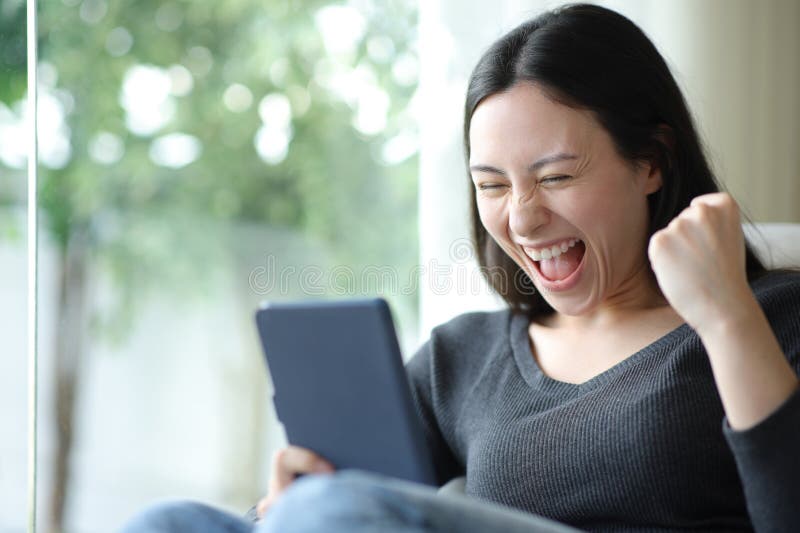Excited asian woman reading ebook at home stock images