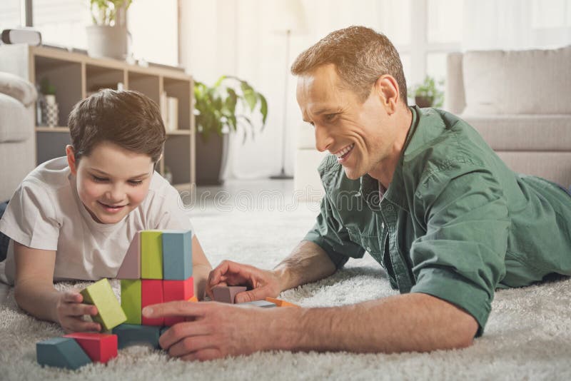 Cheerful family lying on floor and playing with toy royalty free stock images Cheerful family lying on floor and playing with toy royalty free stock images