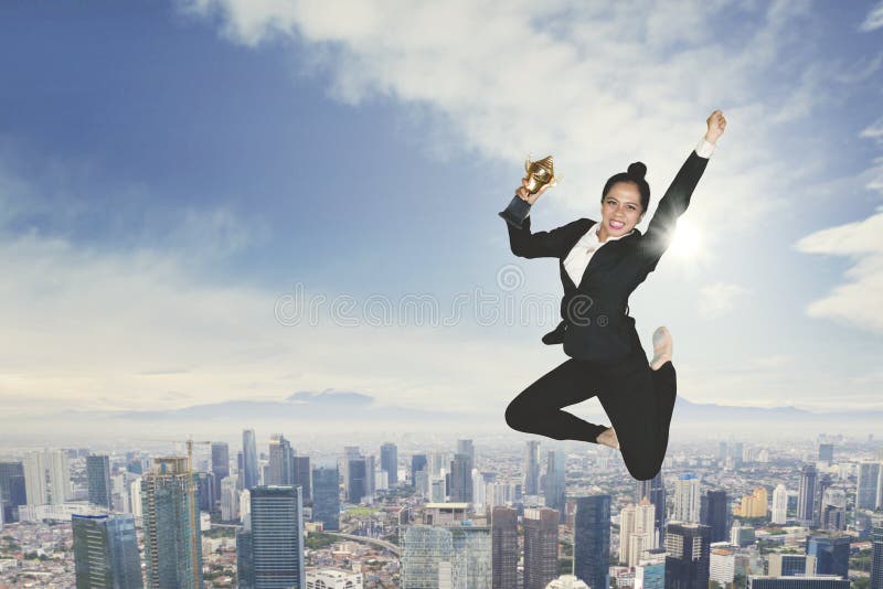Excited businesswoman dancing with a trophy royalty free stock photo Excited businesswoman dancing with a trophy royalty free stock photo