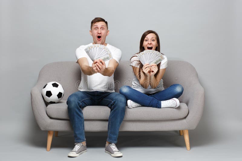Excited couple woman man football fans cheer up support favorite team, holding fan of money in dollar banknotes, cash stock photos Excited couple woman man football fans cheer up support favorite team, holding fan of money in dollar banknotes, cash stock photos