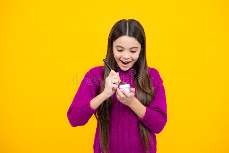 Excited face. Child girl 12, 13, 14 years old making beauty make up with powder and brush. Beautiful teenager applying stock photos