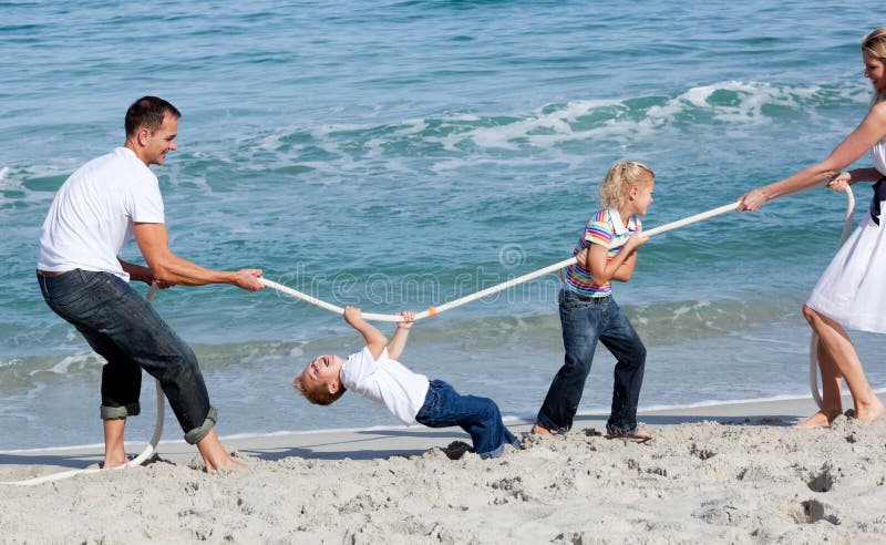 Excited family playing tug of war at the beach