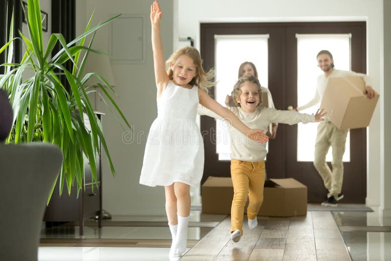 Excited funny kids boy and girl running inside luxury big modern house on moving day, cute children entering exploring new home, happy young family buying real estate, mortgage and relocation concept. Excited funny kids boy and girl running inside luxury big modern house on moving day, cute children entering exploring new home, happy young family buying real estate, mortgage and relocation concept