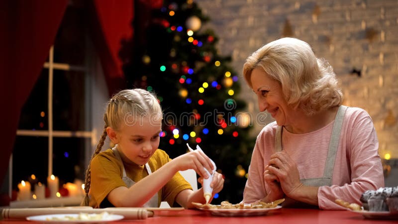 Excited girl decorating Xmas cookies with granny, family festive traditions royalty free stock images Excited girl decorating Xmas cookies with granny, family festive traditions royalty free stock images
