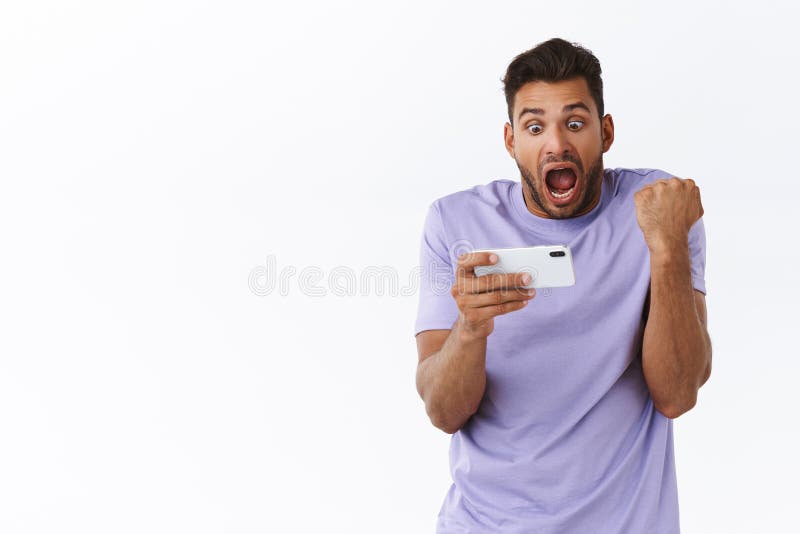 Excited good-looking bearded man in purple t-shirt, winning, passed level in mobile game, fist pump, clench arm and