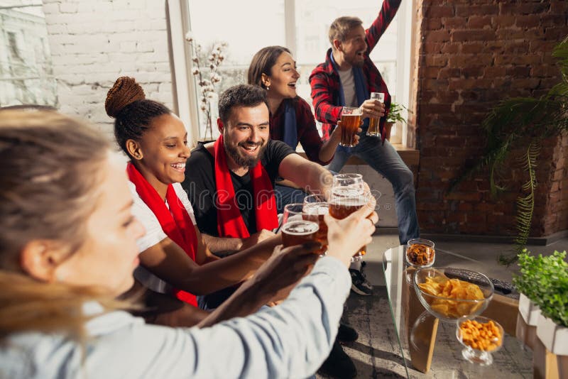 Excited group of people watching football, sport match at home.