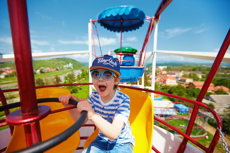 Excited kid riding on ferris wheel in amusement park stock image