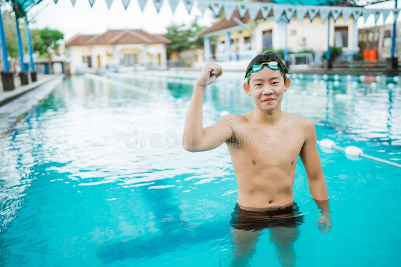 excited male athlete poses with fists in the pool after entering the finish line