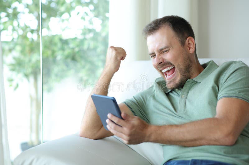 Excited man reading an ebook celebrating royalty free stock photo