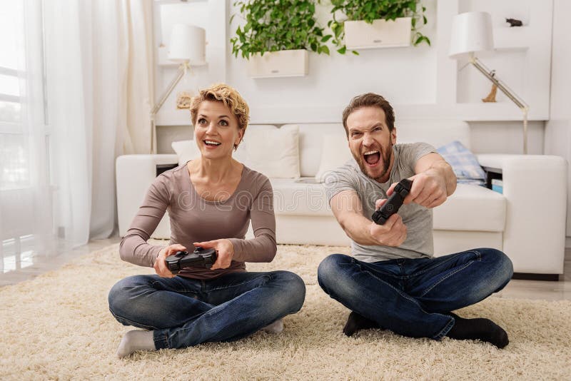 Joyful couple winning video games with joystick on console in