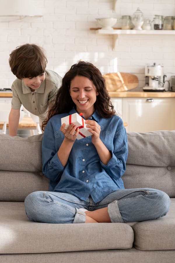 Excited mommy hold birthday gift from small kid. Boy congratulating mom on mother day with present