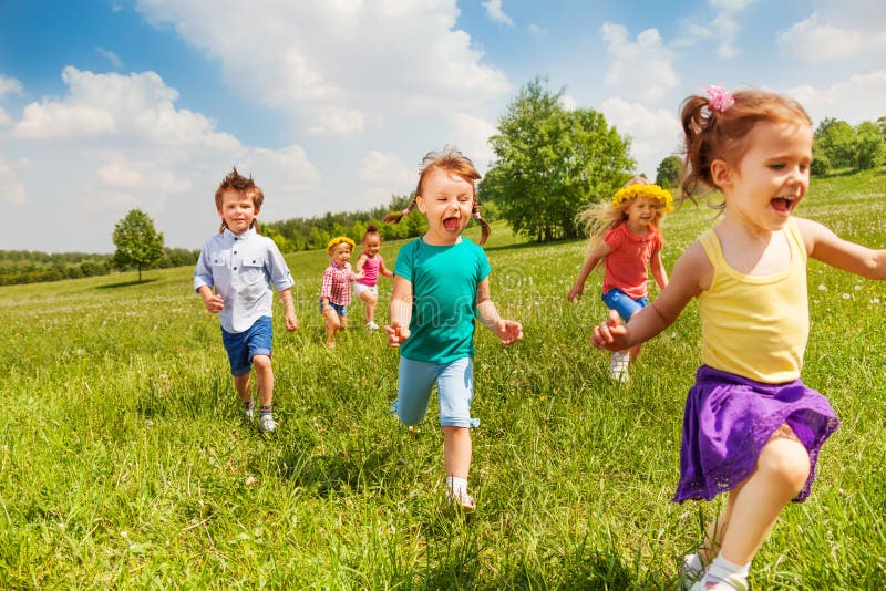 Nadšený beží deti v zelenom poli v lete hrať spolu.