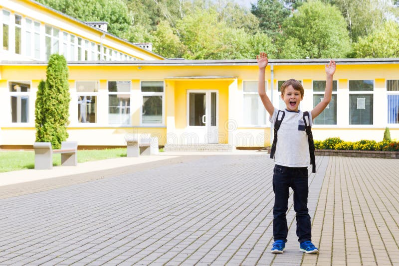 Excited Schoolboy With Hands Up Near The School