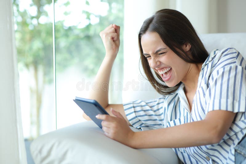 Excited woman reading an ebook celebrating plot twist stock photography