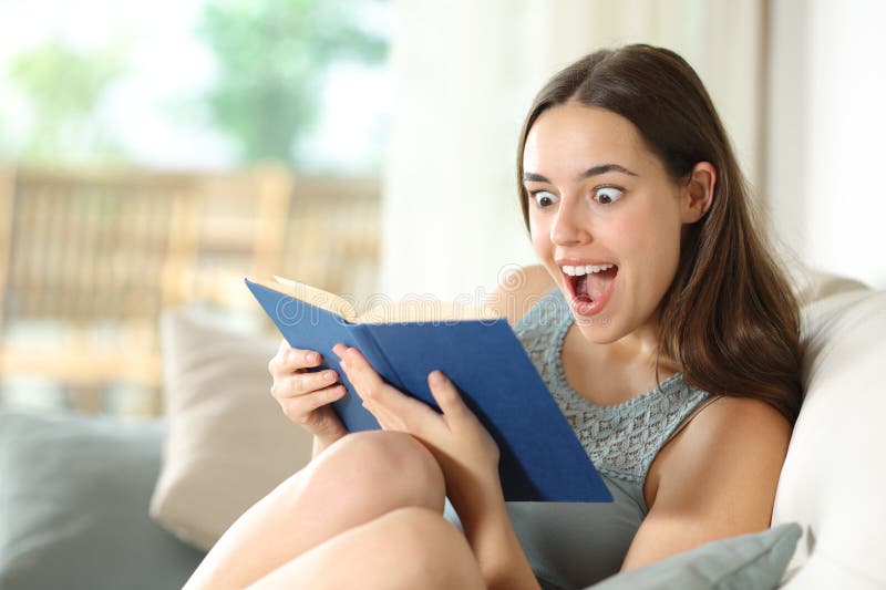 Excited woman reading paper book sitting in a house interior royalty free stock image