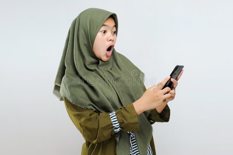 Excited young Asian Muslim woman shock look at smartphone get best gift / voucher / discount