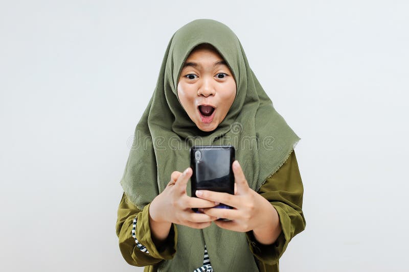 Excited young Asian Muslim woman shock look at smartphone get best gift / voucher / discount