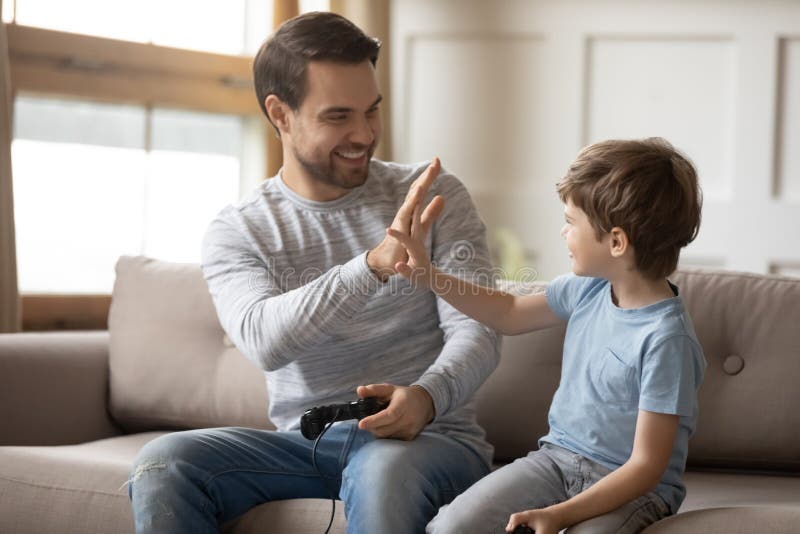 Excited young father giving high five to happy little son.