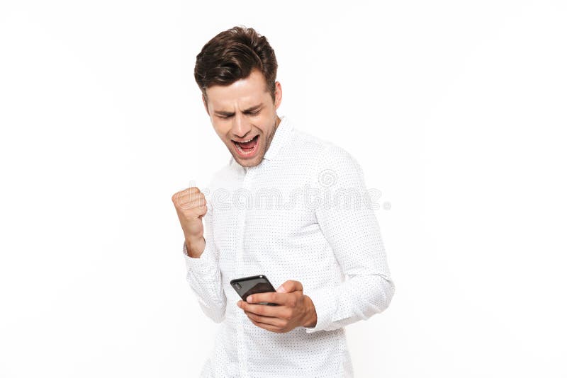 Excited человек при короткие темные волосы держа smartphone и clenchin стоковые изображения rf
