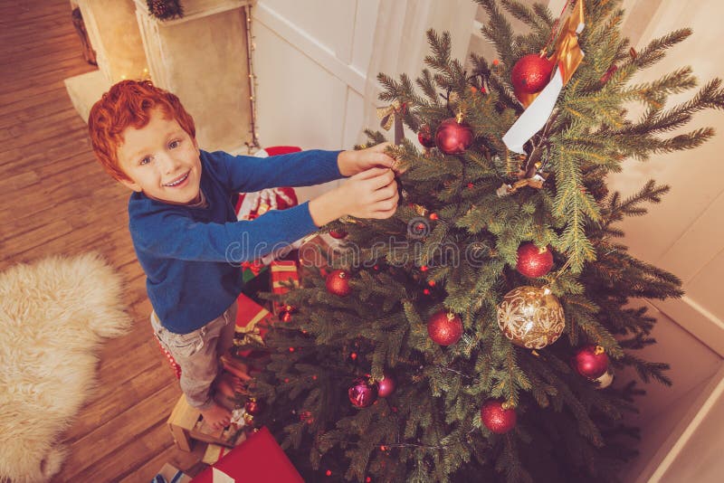 Top view of cute red-haired boy decorating Christmas tree royalty free stock photo Top view of cute red-haired boy decorating Christmas tree royalty free stock photo