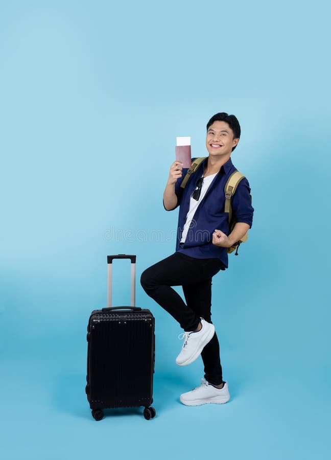 Excité beau asiatique touriste masculin portant des vêtements décontractés tenant un billet d'avion isolé sur fond bleu clair. air photo stock