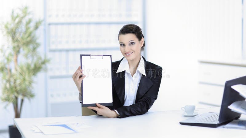 Executive business woman showing blank sheet,sitting at her Desk stock photo Executive business woman showing blank sheet,sitting at her Desk stock photo