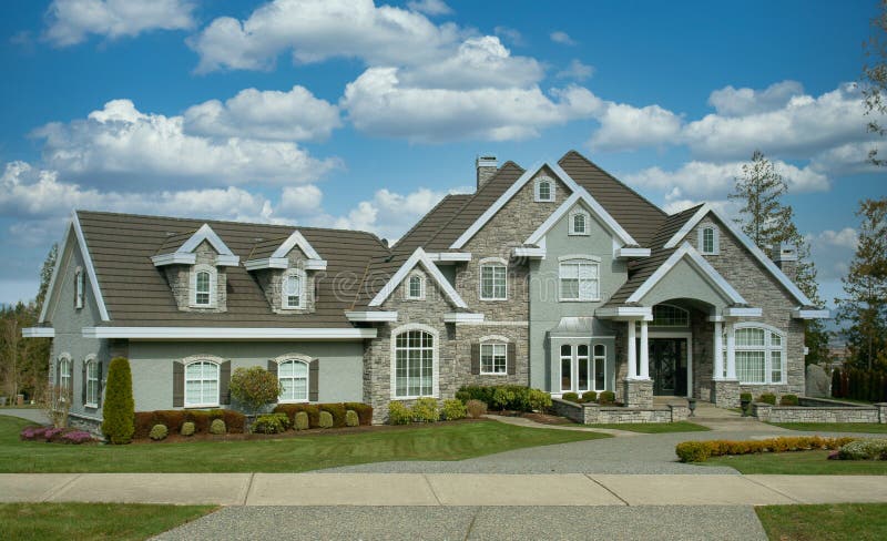 Executive designed custom home showing street front elevation with rock and stucco siding with a puffy white cloudy sky background. House front elevation stock images, royalty-free photos and pictures