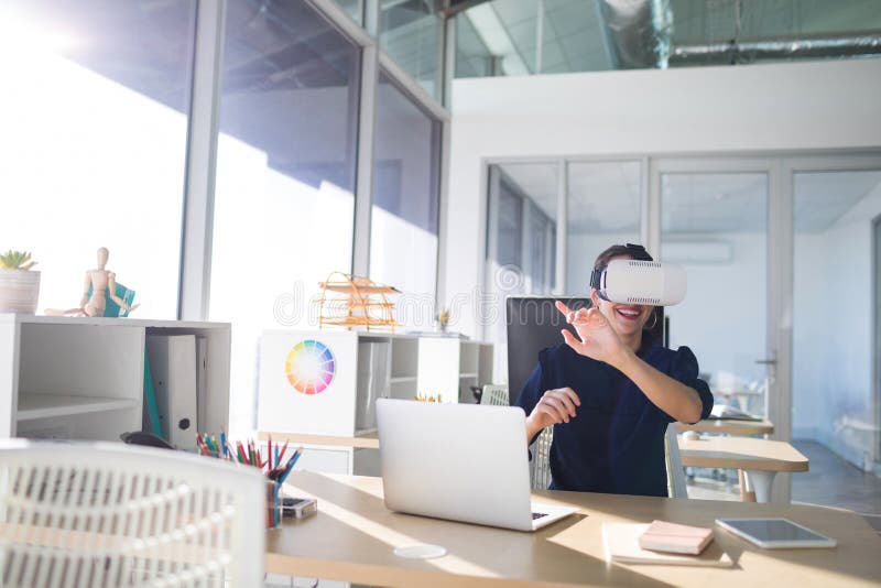 Executivo fêmea que usa auriculares da realidade virtual em sua mesa imagem de stock royalty free Executivo fêmea que usa auriculares da realidade virtual em sua mesa imagem de stock royalty free
