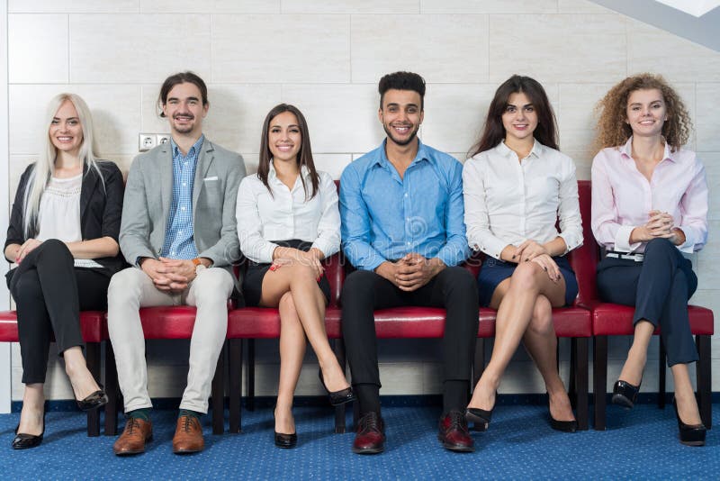 Executivos da reunião de grupo que senta-se na linha fila, recrutamento Job Interview de espera da multidão dos empresários fotografia de stock royalty free