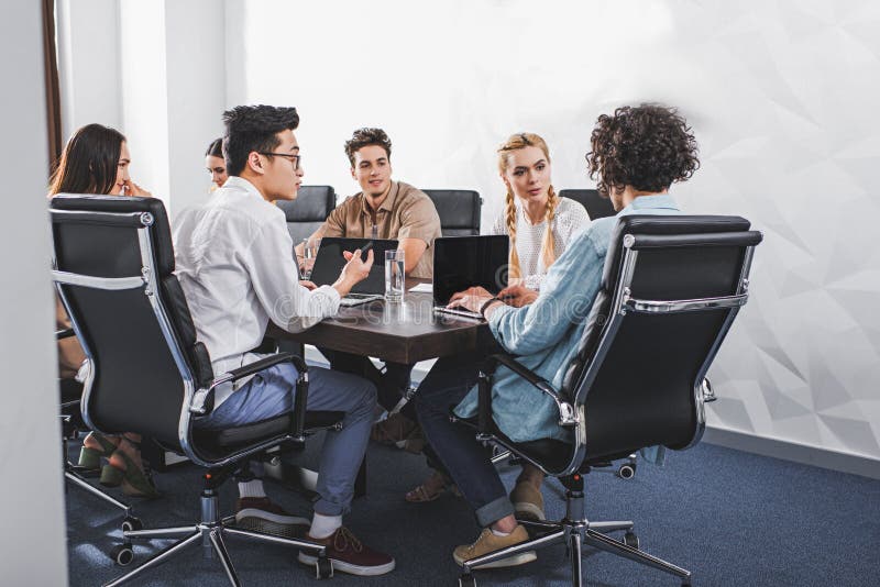 executivos multi-étnicos que têm a discussão na tabela com os portáteis em moderno imagens de stock royalty free executivos multi-étnicos que têm a discussão na tabela com os portáteis em moderno imagens de stock royalty free