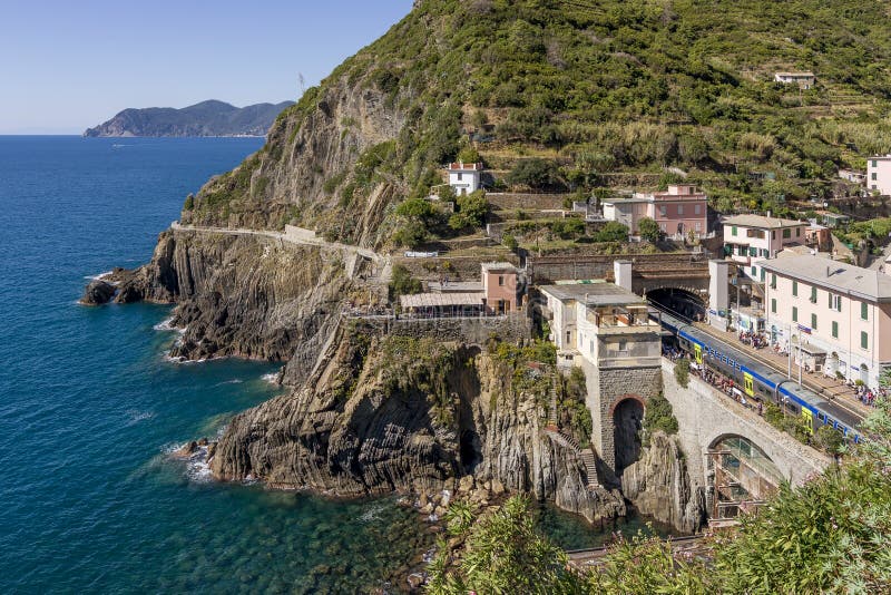 Exercez-vous dans la station de train de Riomaggiore avec de la La de ` par l'intermédiaire du ` d'amore de ` de vallon à l'arriè photographie stock libre de droits Exercez-vous dans la station de train de Riomaggiore avec de la La de ` par l'intermédiaire du ` d'amore de ` de vallon à l'arriè photographie stock libre de droits