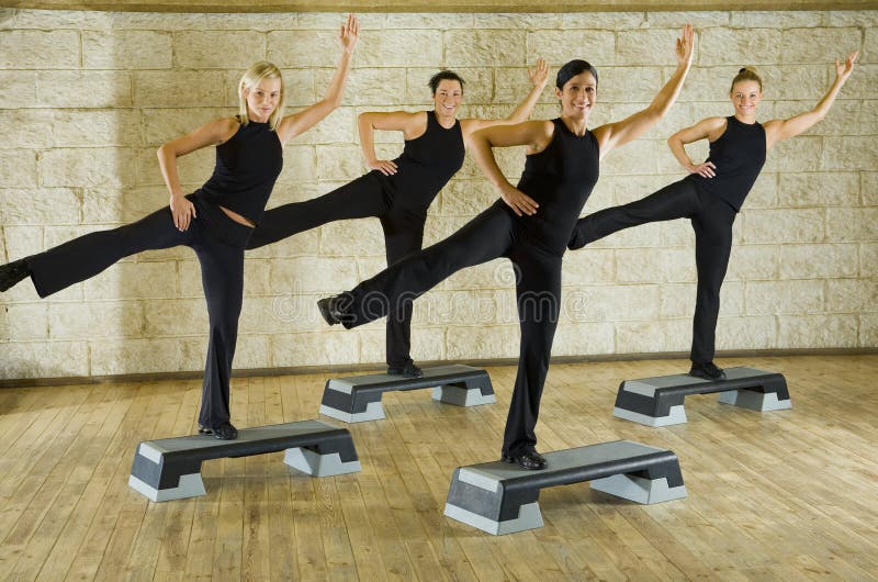 A group of women exercising in the fitness club. They're smiling and looking at camera. Front view. A group of women exercising in the fitness club. They're smiling and looking at camera. Front view.