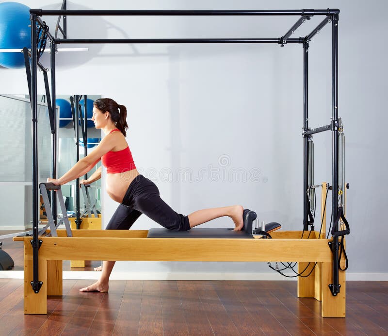 Exercício de cadillac do reformista dos pilates da mulher gravida fotos de stock Exercício de cadillac do reformista dos pilates da mulher gravida fotos de stock