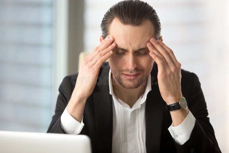 Exhausted businessman having a headache after long work hours. stock photos Exhausted businessman having a headache after long work hours. stock photos