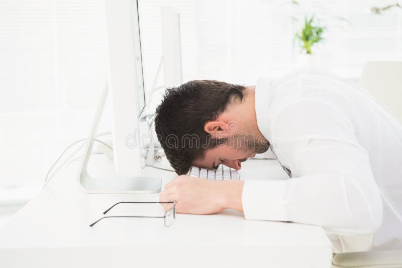Exhausted businessman napping on keyboard in his office
