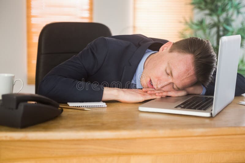 Exhausted businessman sleeping on his laptop in the office
