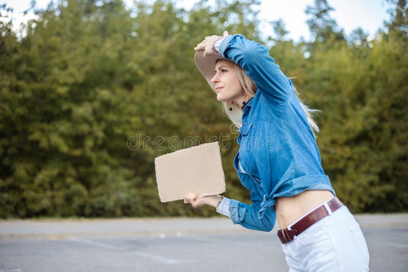 Exhausted Curious Blond Woman Hold Hat Hitchhiking With Blank Cardboard Plate And Look For Car