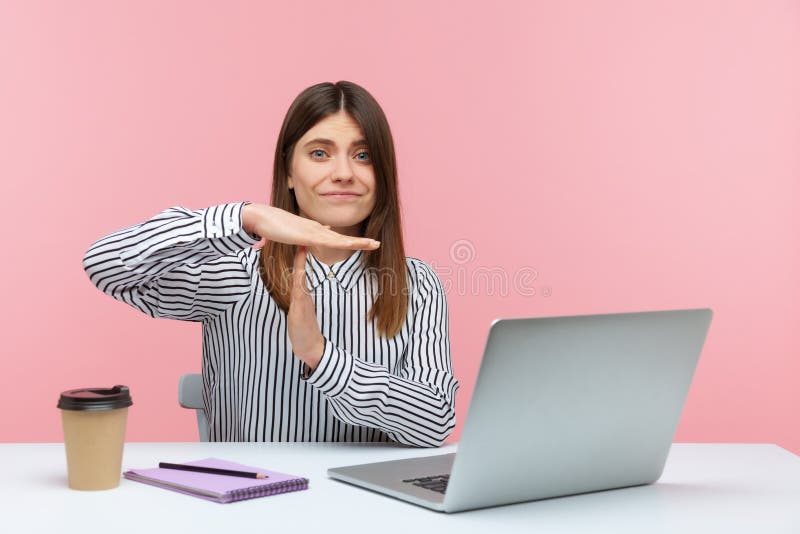 Exhausted overworked woman showing time out gesture, asking for break sitting at workplace with laptop, professional burnout