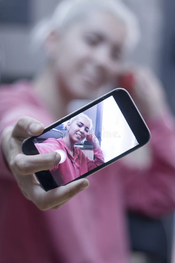 Exhibición de la demostración de la mujer joven del teléfono celular móvil que toma un selfie foto de archivo Exhibición de la demostración de la mujer joven del teléfono celular móvil que toma un selfie foto de archivo