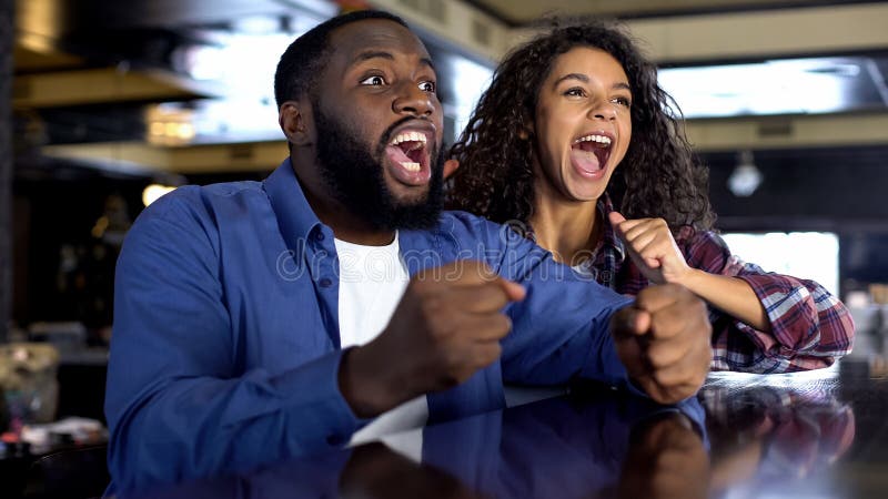 Exited multiethnic couple rooting for national team watching game, entertainment