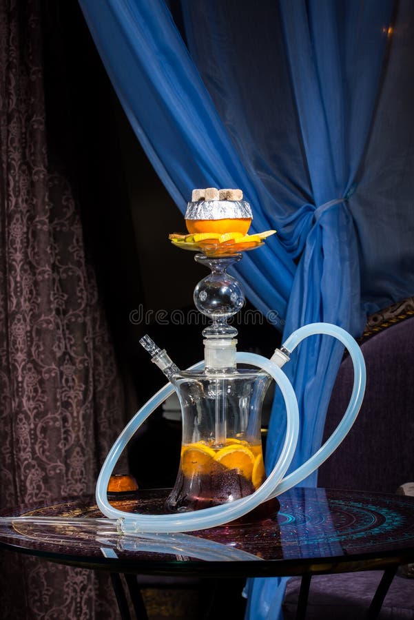 Exotic hookah with orange on top over blue background